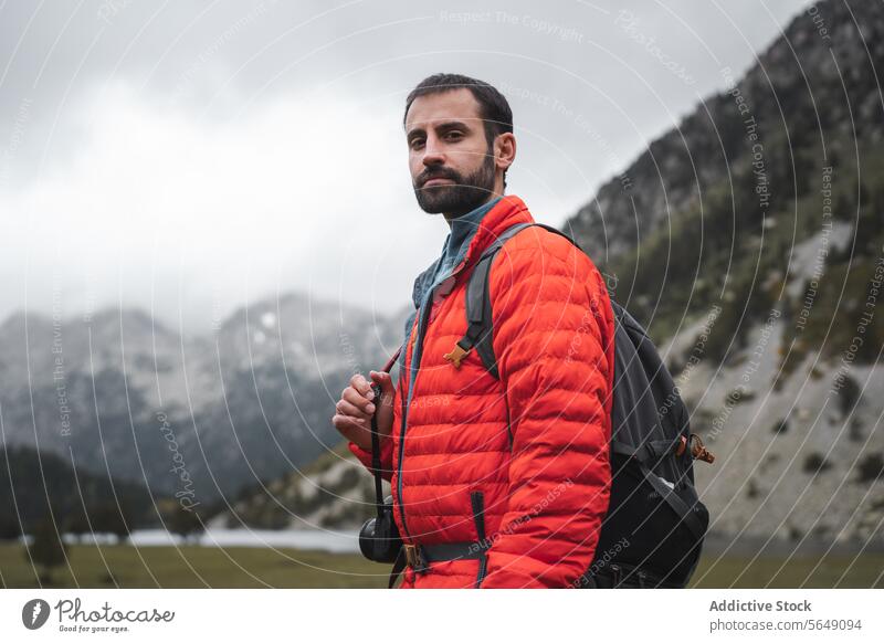 Erwachsener Mann in orangefarbener Winterjacke beim Wandern in den Bergen Wanderung Tourist Porträt selbstbewusst Berge u. Gebirge Jacke Nationalpark Backpacker