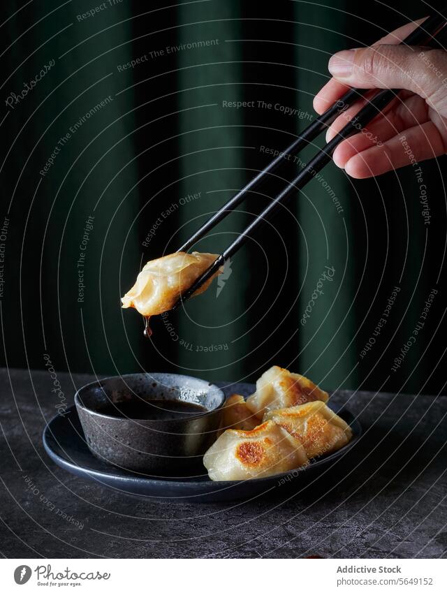 Unkenntlich gemachte Person, die Gyoza mit Stäbchen und Soße in einer Schüssel hält Knödel Essstäbchen Asiatische Küche Saucen Schalen & Schüsseln Lebensmittel