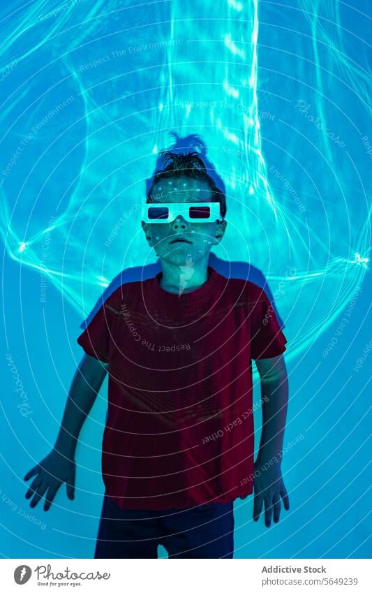 Niedliches Kind mit 3D-Brille im Neonstudio mit blauen Lichtern Junge 3d glühen neonfarbig unterhalten sorgenfrei futuristisch leuchten Kindheit niedlich Frisur