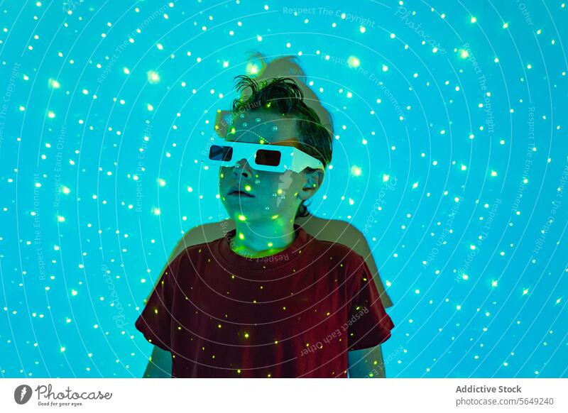 Niedliches Kind mit 3D-Brille im Neonstudio mit blauen Lichtern Junge 3d glühen neonfarbig unterhalten sorgenfrei futuristisch leuchten Kindheit niedlich Frisur