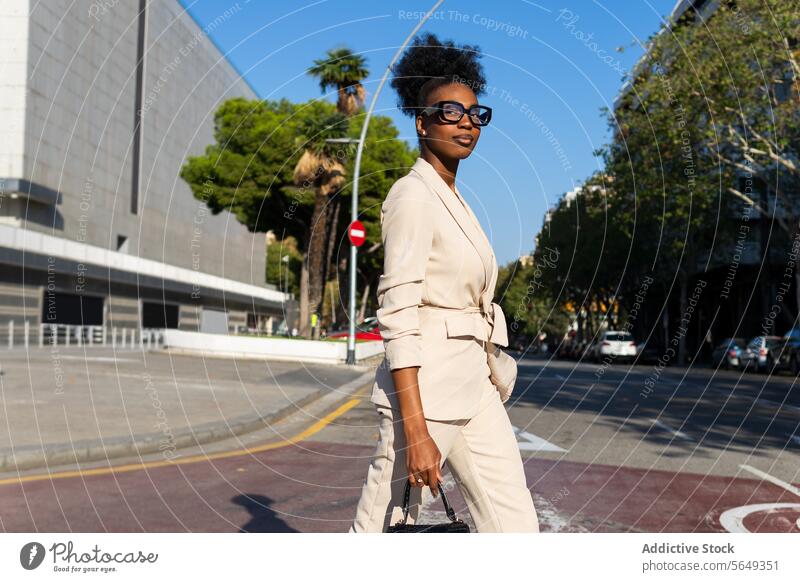 Seitenansicht einer lächelnden schwarzen Geschäftsfrau auf der Straße professionell Überfahrt laufen Geldbörse Großstadt modisch sonnig Sonnenlicht Arbeitsweg