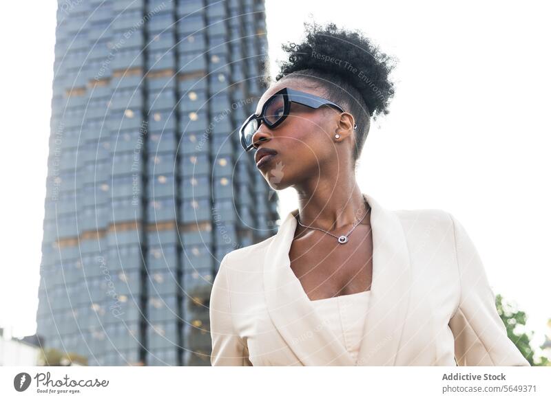 Niedriger Winkel der Mode schwarze Unternehmerin in smart casual Blick weg, während gegen Gebäude stehen Geschäftsfrau modisch Brille Brötchen niedriger Winkel