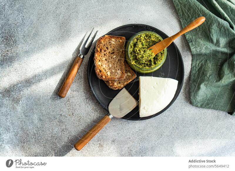 Teller mit leckerem Roggenbrot, Käse und Pestosauce Saucen geschmackvoll selbstgemacht Brot Schalen & Schüsseln Besteck dienen Tisch Lebensmittel Küche