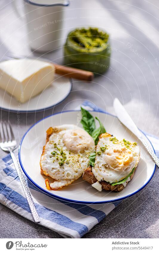 Teller mit einer gesunden Mahlzeit aus Toast mit Spiegeleiern, Blattspinat und Soße Saucen Gesundheit Zuprosten Pesto Frühstück Kraut dienen Käse lecker grün