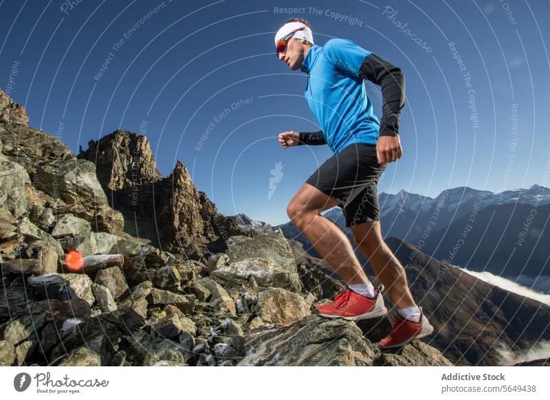 Von unten, männlicher Läufer in Sportkleidung Sportbekleidung steigen felsig alpin Weg zerklüftet Gipfel Berge u. Gebirge Nachlauf Aktion fokussiert im Freien