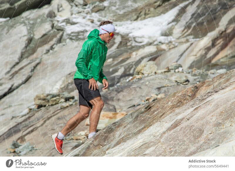 Konzentrierter Trailrunner beim Aufstieg über einen felsigen Abhang Läufer Nachlauf Berge u. Gebirge Sportbekleidung rennen Besteigung Berghang im Freien