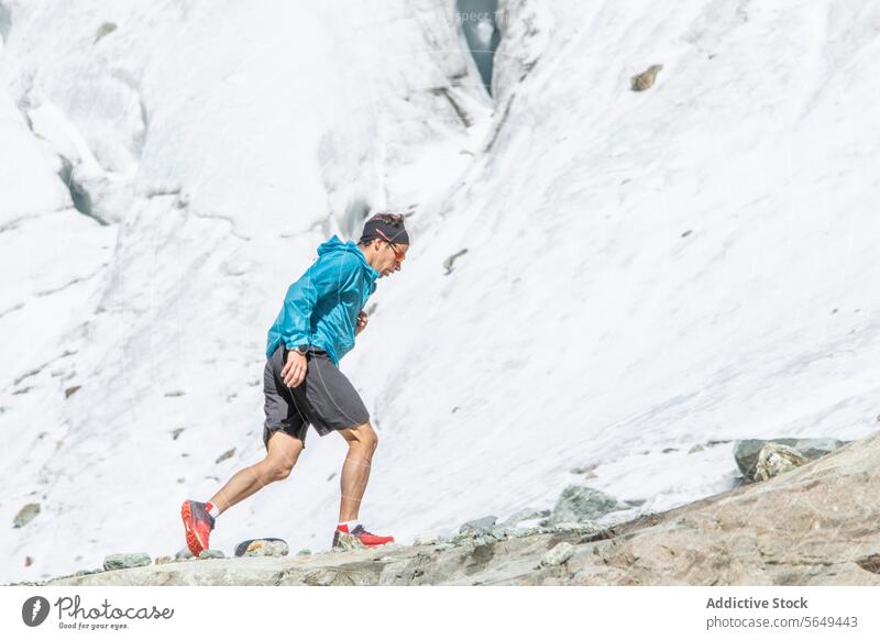 Konzentrierter Trailrunner, der einen felsigen Abhang hinaufsteigt Läufer Nachlauf Berge u. Gebirge Sportbekleidung rennen Besteigung Berghang im Freien Fitness