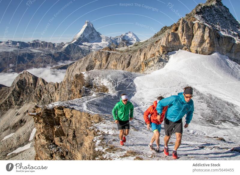 Drei Trailrunner in bunter Kleidung laufen auf einem verschneiten Berg Nachlauf Läufer Berge u. Gebirge Schnee Gipfel Weg rennen sportlich Sport Ausdauer Übung
