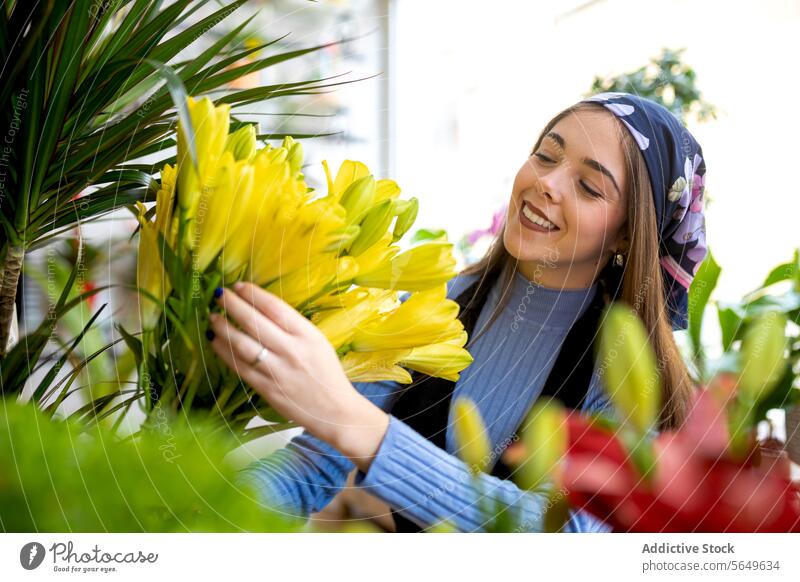 Glückliche Frau arrangiert gelbe Blumen in der Floristik Blumenhändler Besitzer einrichten Lächeln Arbeit Blumenstrauß Blüte Blütezeit geblümt frisch Job jung