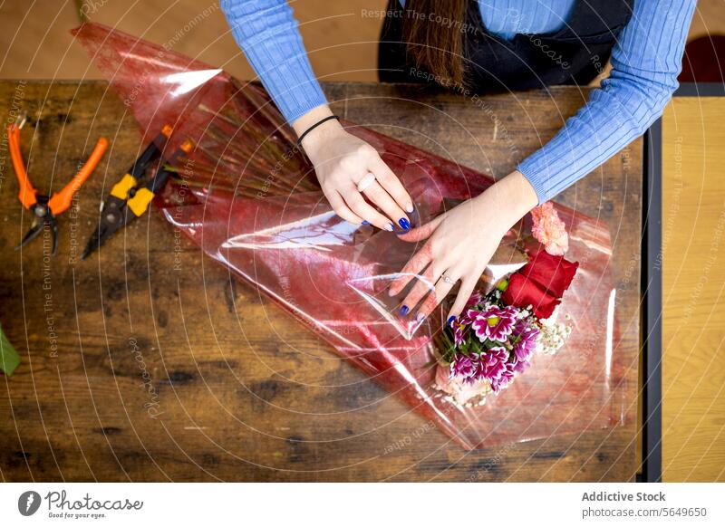 Unbekannte Frau arrangiert Blumenstrauß auf dem Tisch Blumenhändler Kunststoff umhüllen einrichten vorbereiten Dekoration & Verzierung jung Floristik Hülse