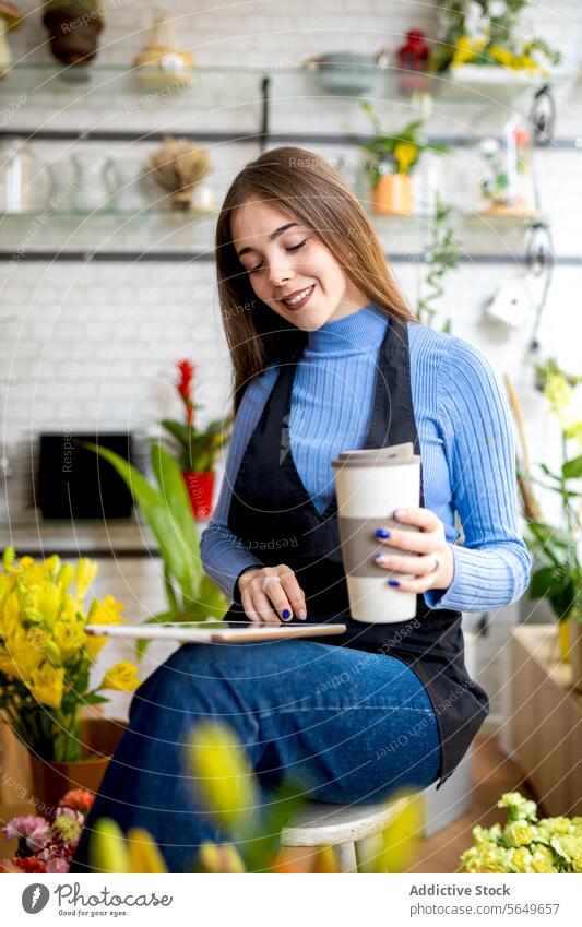Glückliche Besitzerin mit Tablet im Blumenladen Frau Blumenhändler benutzend digital Tablette Kaffee Arbeit Werkstatt Lächeln jung positiv Gerät Tasse