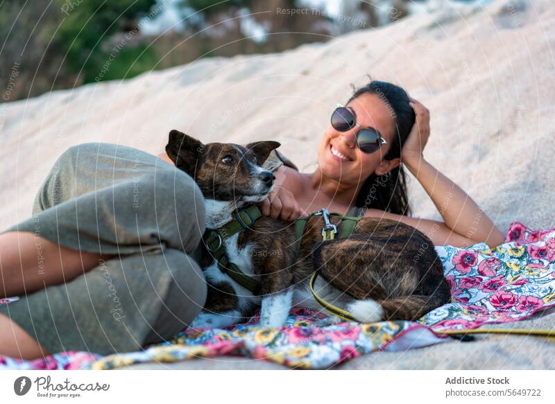 Frau mit Haustier rastet am Strand Tourist Hund Lügen Sand Glück Sonnenbrille bezaubernd Lächeln Decke sich[Akk] entspannen Urlaub heiter schön Tier
