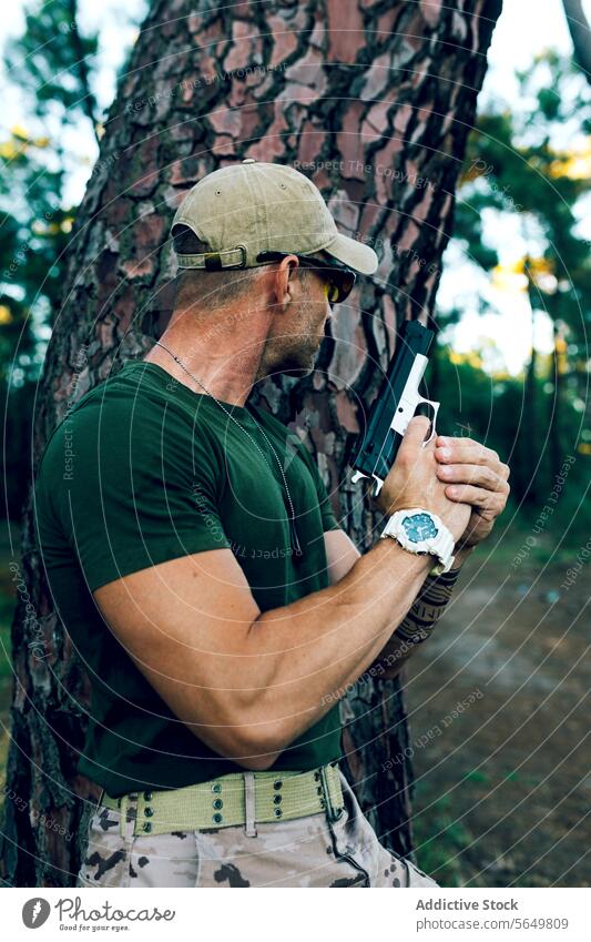 Seitenansicht von Military Soldat mit Waffe versteckt hinter Baum gegen Wald Mann Kommando Pistole Armee speziell zwängen Militär Unschärfe Missionsstation