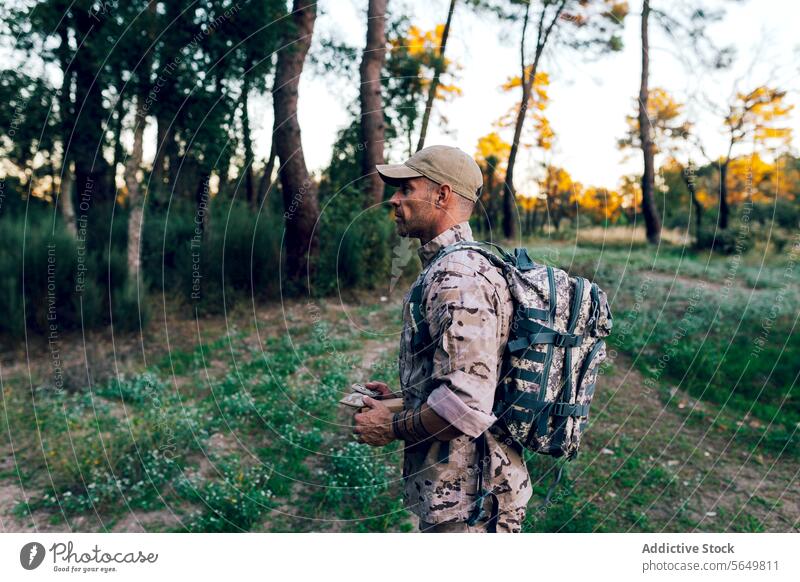 Seitenansicht eines Armeekommandos mit Mütze und Rucksack, das eine Kiste im Wald hält Mann Soldat Militär Tarnung Uniform Kasten Kommando