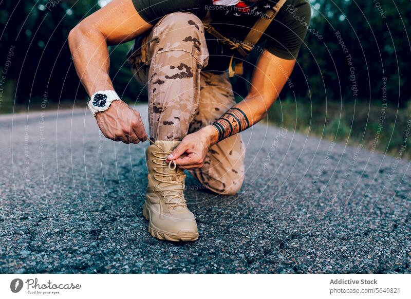 Crop anonym Reife männliche Kommando binden Schnürsenkel während kniend auf der Straße Mann Soldat Schuh Kopplungsbindung Schuhbänder keuchen Unschärfe Militär