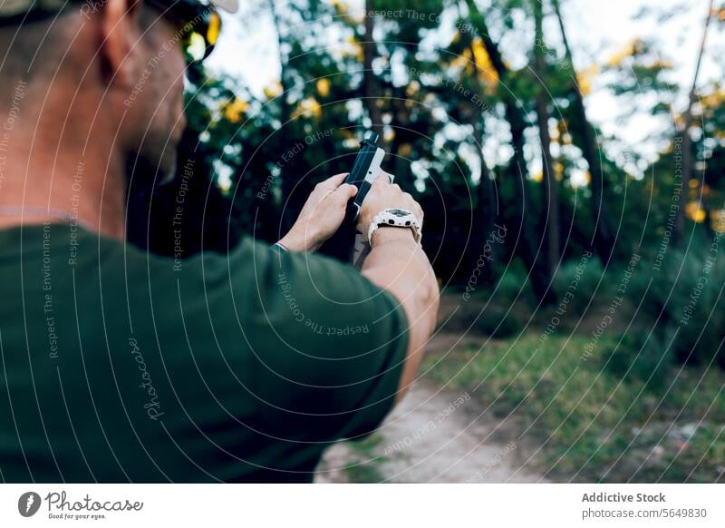 Rückenansicht eines anonymen Militärs, der eine Waffe gegen einen Wald hält Mann Kommando Pistole praktizieren Schießen Training Ziel unkenntlich Armee speziell