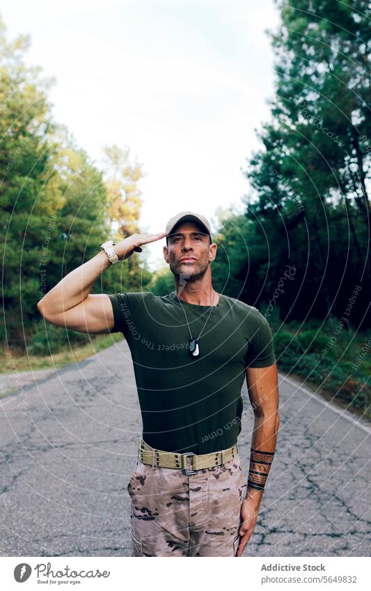 Selbstbewusstes Kommando einer Spezialeinheit auf der Straße, das stolz vor dem Wald salutiert Mann Soldat Militär Salutieren Stolz Tarnung selbstbewusst
