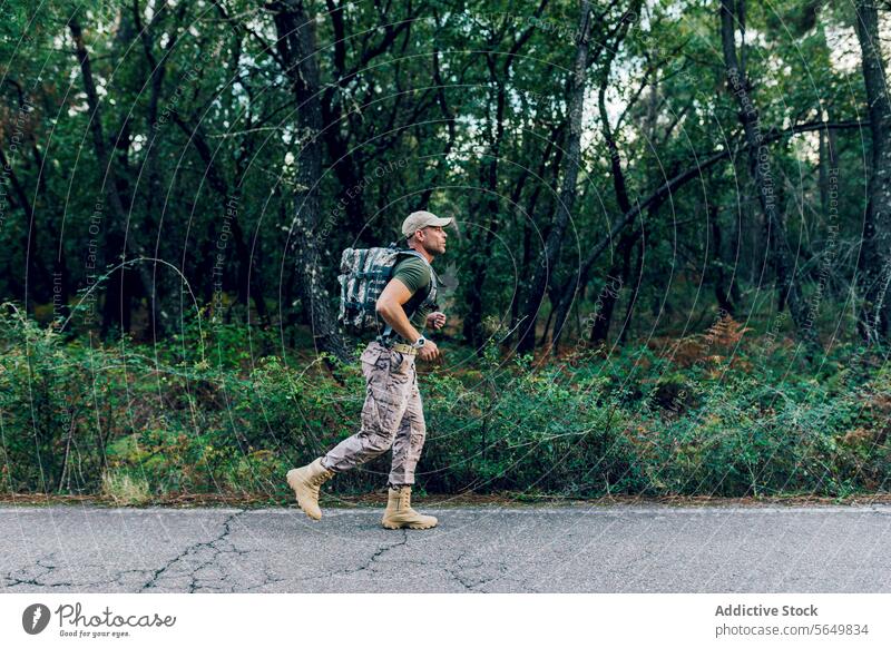 Ganzkörpertraining von Soldier beim Joggen durch Pflanzen und Bäume Mann Kommando marin rennen Rucksack Straße Fitness Uniform Training Baum Soldat Straßenrand