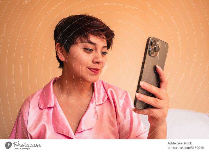 Lächelnde junge Frau beim Surfen auf dem Smartphone im Schlafzimmer benutzend Browsen zu Hause soziale Netzwerke Glück Telefon Internet Nachtwäsche Funktelefon