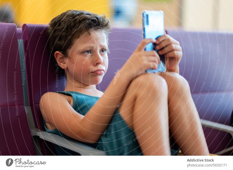 Junge benutzt Smartphone im Wartebereich eines Flughafens Wartesaal Sitzgelegenheit Kind reisen Terminal Passagier digital Technik & Technologie Entertainment