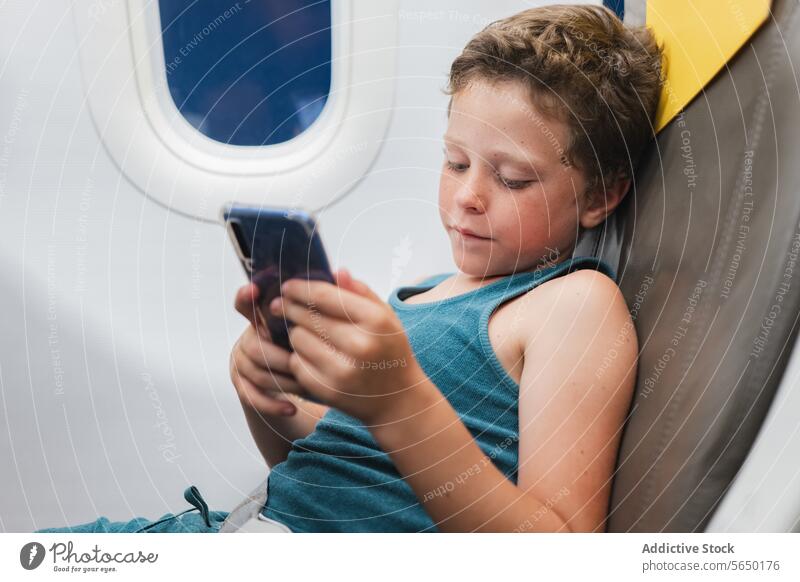 Junger Junge im Flugzeug in Tablet vertieft Kind Sitz Tablette Funktelefon Telefon Bildschirm Technik & Technologie reisen Fenster jung Passagier digital Gerät