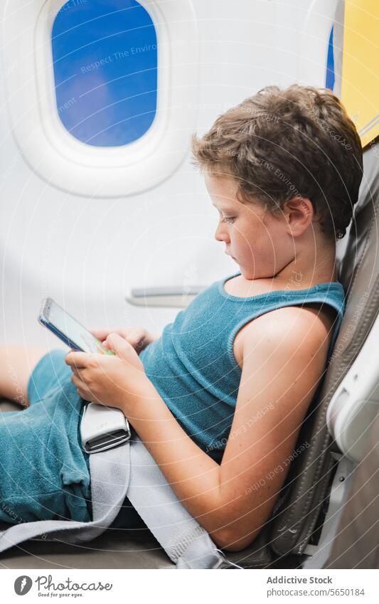 Junger Junge im Flugzeug in Tablet vertieft Kind Sitz Tablette Bildschirm Technik & Technologie reisen Fenster jung Passagier digital Gerät Entertainment
