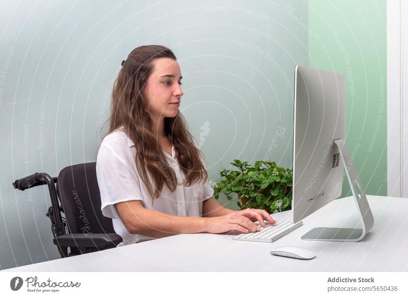 Junger Berufstätiger arbeitet im Rollstuhl am Computer im Büro Frau professionell arbeiten modern hell jung Schreibtisch Arbeit Job Technik & Technologie