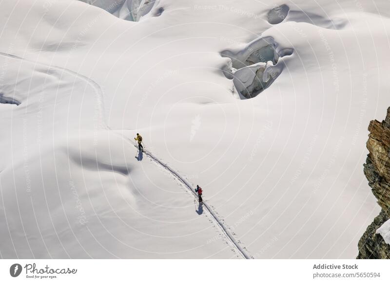 Hoher Winkel von anonymen Skifahrern in warmer Kleidung beim Überqueren eines schneebedeckten Gletschers in Zermatt, Schweiz Schnee Eis Kamm Nachlauf alpin
