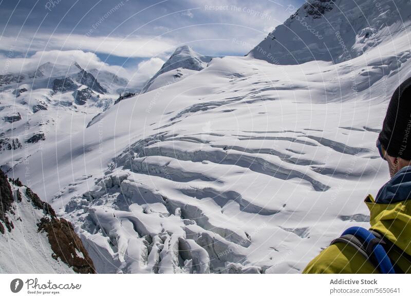 Crop Unerkennbar männlicher Tourist in warmer Kleidung und Sonnenbrille bewundern verschneite Landschaft unter bewölktem Himmel in Zermatt Mann Wanderer Schnee