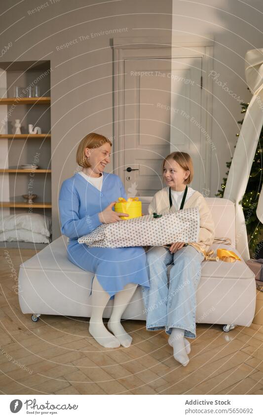Mutter und Tochter tauschen zu Hause fröhlich Geschenke aus Wechseln Sofa Lächeln präsentieren gelb eingewickelt Feier Familie Fröhlichkeit Freude Bonden