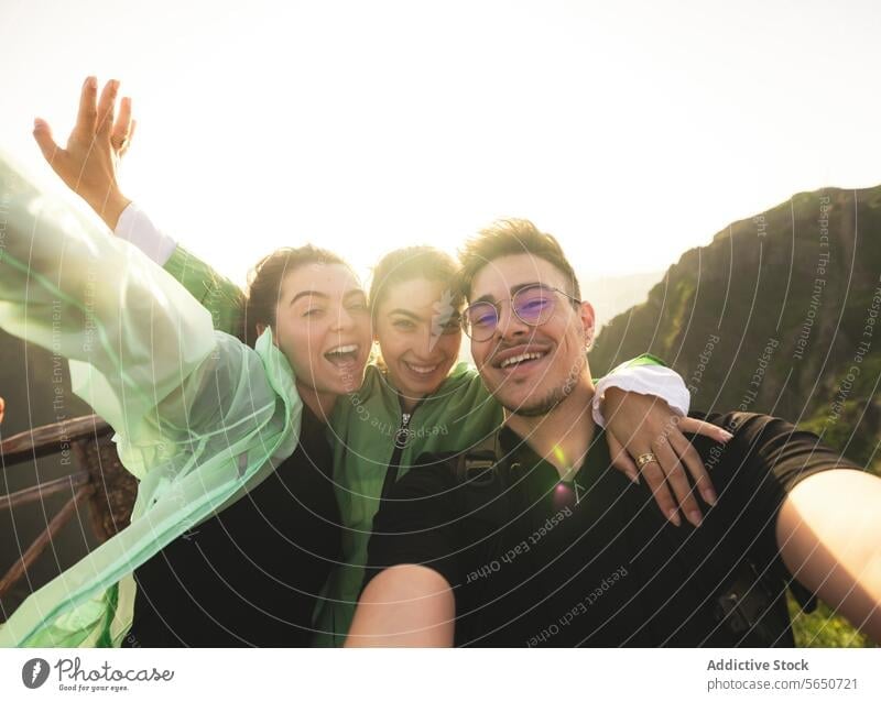 Porträt von fröhlichen kaukasischen aktiven jungen Freunden, die ein Selfie machen und dabei in die Kamera schauen, auf einem Berggipfel während des Sonnenaufgangs beim Wandern am Wochenende