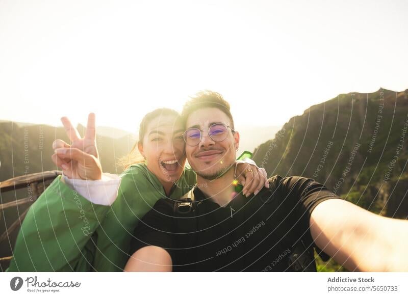 Glückliche Freunde auf dem Berggipfel bei Sonnenaufgang Mann Frau Lächeln Selfie Siegeszeichen hintergrundbeleuchtet Porträt heiter Berge u. Gebirge