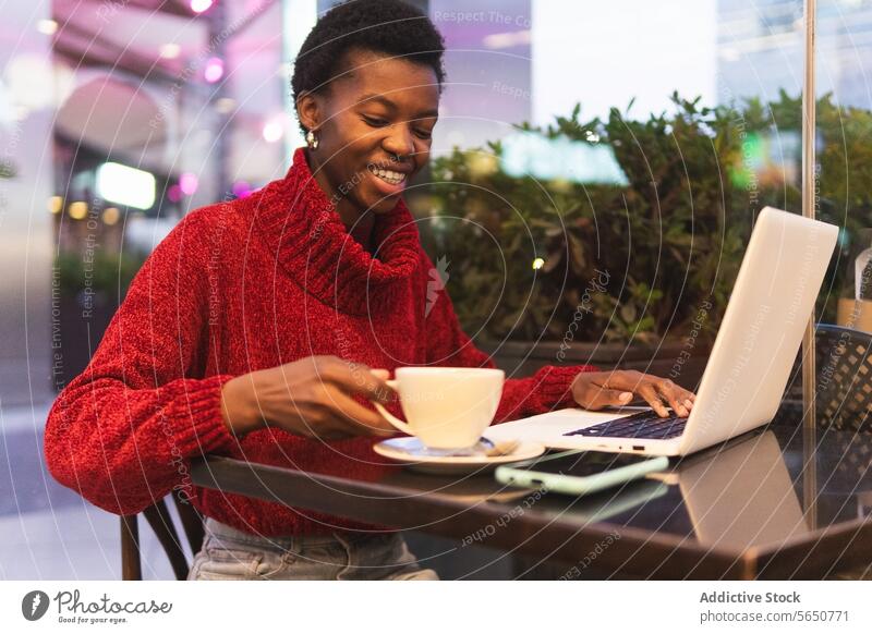 Freiberufliche schwarze Frau arbeitet an einem Laptop in einem Café freiberuflich benutzend trinken Cappuccino Kaffee Tippen Arbeit Erwachsener Afroamerikaner
