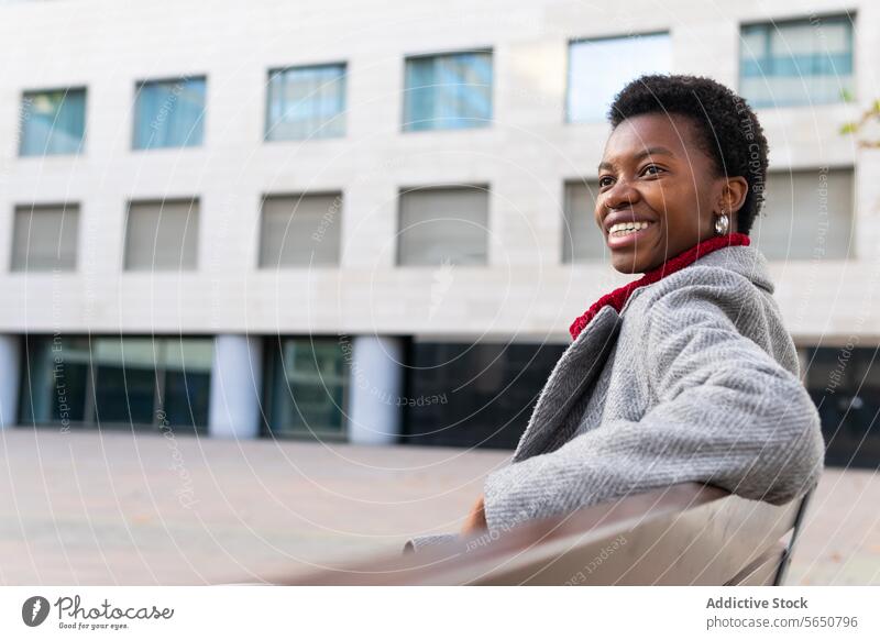 Fröhliche schwarze Frau entspannt sich auf einer Bank ruhen Großstadt Wochenende Freizeit Stadt Herbst Straße Park genießen zufrieden Lächeln Glück heiter