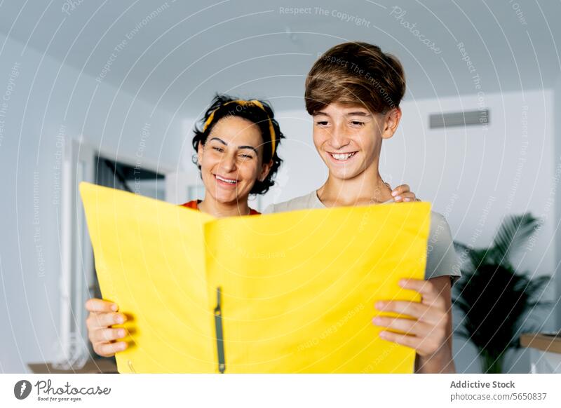 Mutter und Sohn amüsieren sich beim Studieren von Dokumenten im gelben Ordner Spaß haben Aktenordner untersuchen genießen Zeit Zusammensein lernen Frau Junge