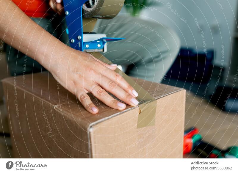 Unerkennbare Frau beim Verpacken eines Kartons mit Klebebandabroller Rudel Schachtel Kasten Spender verlegen knien Erwachsener einziehen Paket sich[Akk] bewegen