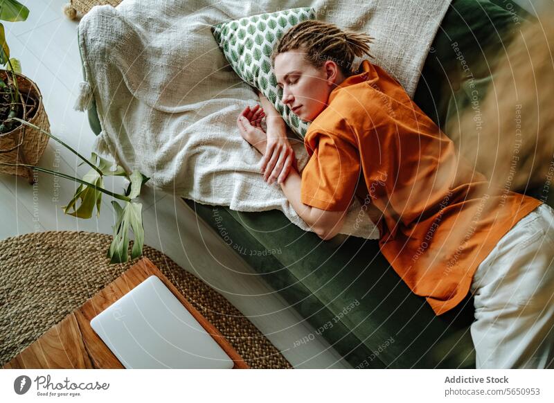 Junge Frau schläft auf bequemen Sofa mit Kissen zu Hause in der Nähe von Laptop schlafen Appartement Liege Komfort sich[Akk] entspannen schlafend Mittagsschlaf