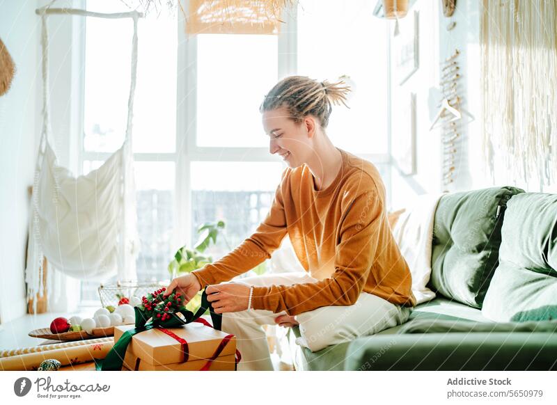 Seitenansicht einer jungen Frau, die zu Hause auf dem Sofa sitzend ein Geschenkpaket vorbereitet Lächeln Überraschung präsentieren Glück Kasten Freude lässig