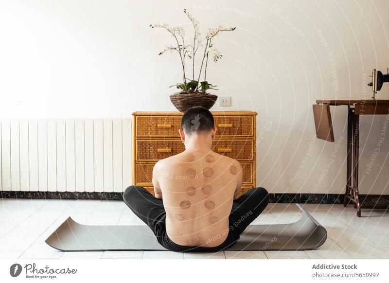 Gesichtsloser Mann im Lotussitz während einer Rehabilitationsmaßnahme Sitzung Dehnung üben Übung fettarm Unterlage anonym sitzen Unterleib Training