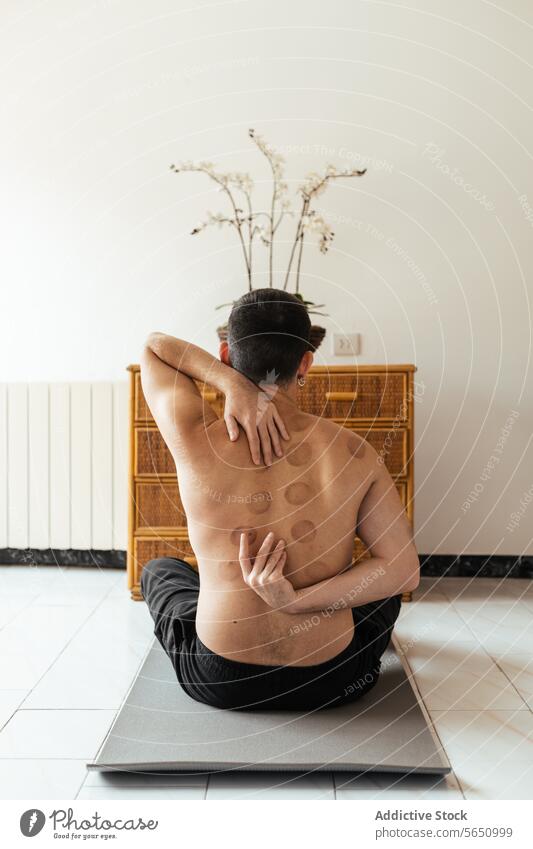 Anonymer Mann bei Dehnungsübungen auf einer Matte zu Hause Yoga Unterlage Übung Mark ohne Hemd üben Wellness Wohlbefinden Gleichgewicht heimwärts Training