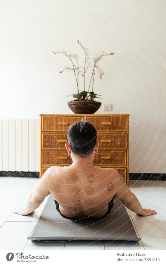 Junger Mann macht Rehabilitationsübungen auf einer Matte zu Hause Dehnung Übung Unterlage ohne Hemd Rücken Therapie Mark Gleichgewicht Wellness passen Erholung