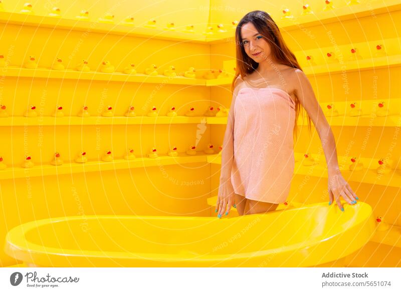Glückliche Frau in ein Handtuch gewickelt Lächeln Rotes Oberteil Stehen gelb Badewanne Gummiente Hintergrund heiter hell Monochrom Mode Stil lässig modern