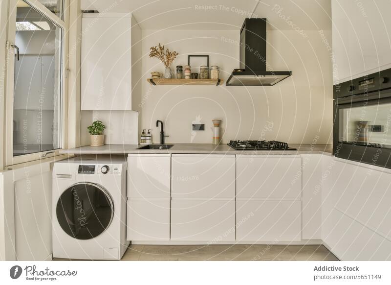 Küche mit Schränken und modernen Geräten Kabinett Wäsche waschen Maschine Ofen Herdabdeckung Arbeitsplatte weiß Licht Wand Fenster Haus Textfreiraum verweilen