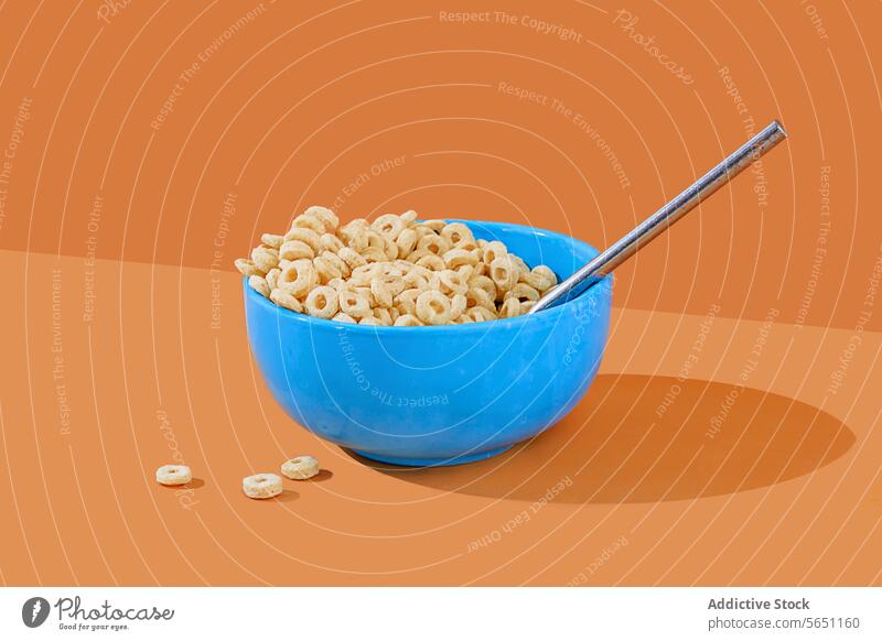 Blaue Müslischale mit Milch auf orangem Hintergrund Schalen & Schüsseln melken Löffel pulsierend blau Frühstück Lebensmittel Snack schlaufenförmig Molkerei
