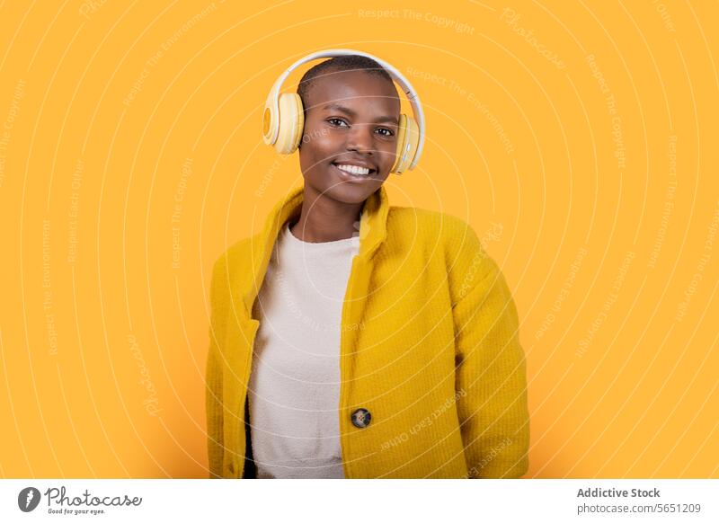 Glückliche schwarze junge Frau, die Musik über drahtlose Kopfhörer hört heiter genießend hören ethnisch Afroamerikaner Drahtlos Lächeln Freizeitkleidung