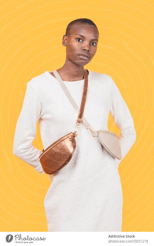Junge schwarze Frau mit Umhängetasche isoliert auf gelbem Hintergrund ernst Babytragetuch Tasche trendy schlank gelber Hintergrund Mode selbstbewusst
