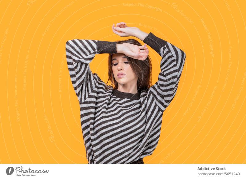 Trendy Frau mit Händen auf dem Kopf isoliert auf gelbem Hintergrund Hände auf dem Kopf trendy lässig attraktiv herabsehend modisch gestreift Muster Stehen