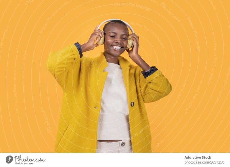 Glückliche schwarze junge Frau, die Musik über drahtlose Kopfhörer hört heiter genießend hören ethnisch Afroamerikaner Drahtlos Lächeln Freizeitkleidung