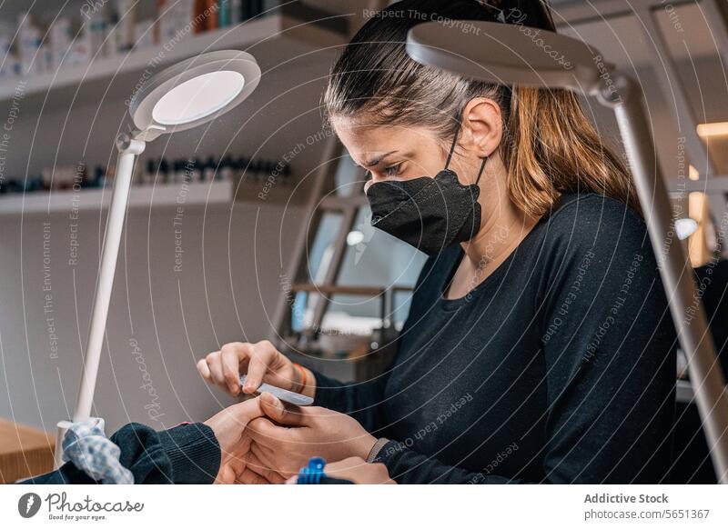Kosmetikerin bei der Maniküre eines Kunden in einem Schönheitssalon Frauen Form Salon Aktenordner Leckerbissen Spa Dienst professionell Verfahren Mundschutz