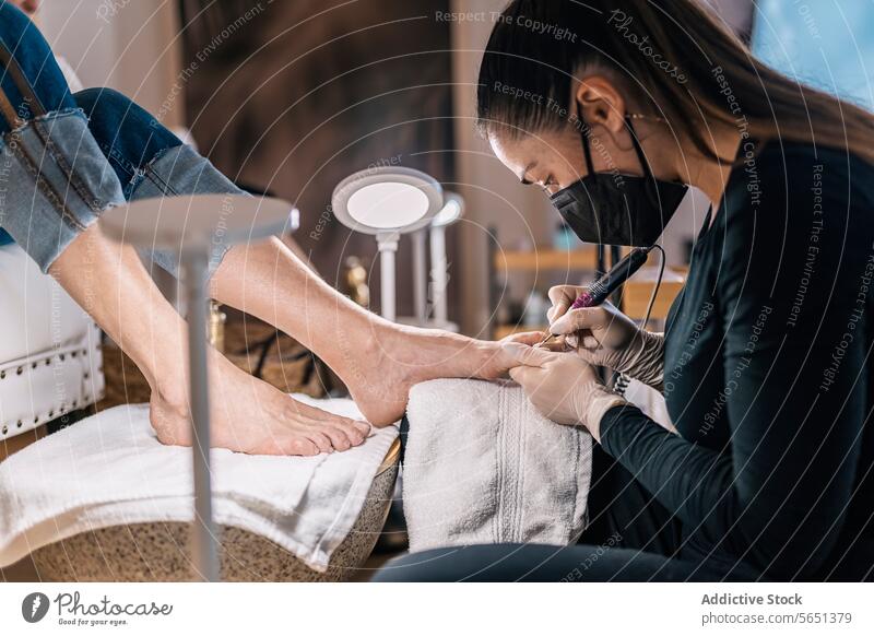 Crop Frau bekommt Pediküre Behandlung in Schönheitssalon Frauen Kosmetikerin Verfahren Künstler Salon Leckerbissen Bein Fuß Klient Kunde Mundschutz